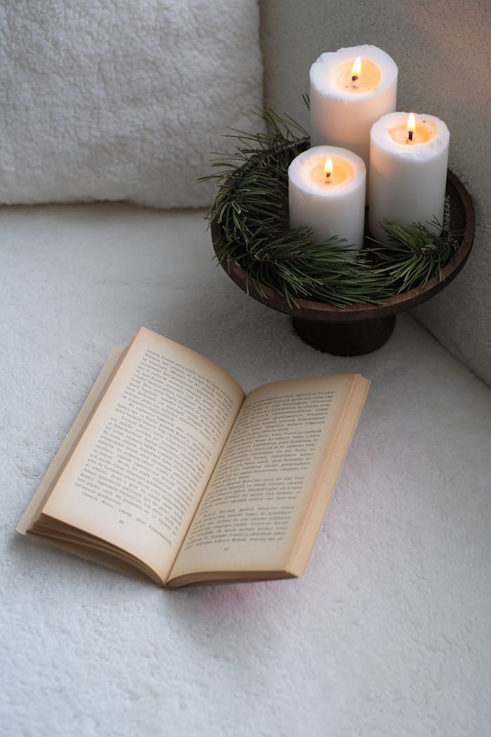 About A serene setup featuring a book and lit candles on a cozy surface, perfect for relaxation.