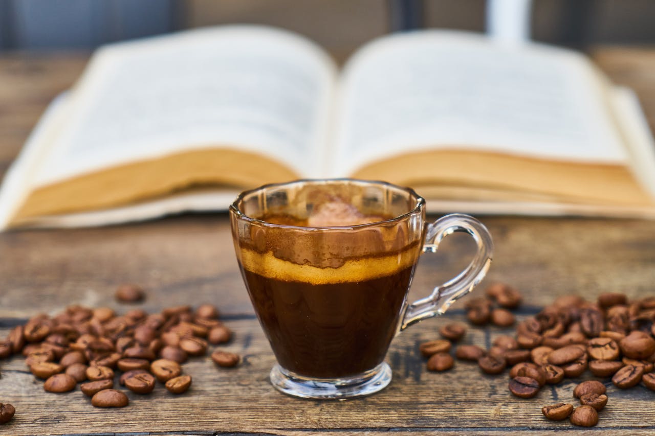 Home A rich espresso cup surrounded by beans and an open book, perfect for a relaxing break.